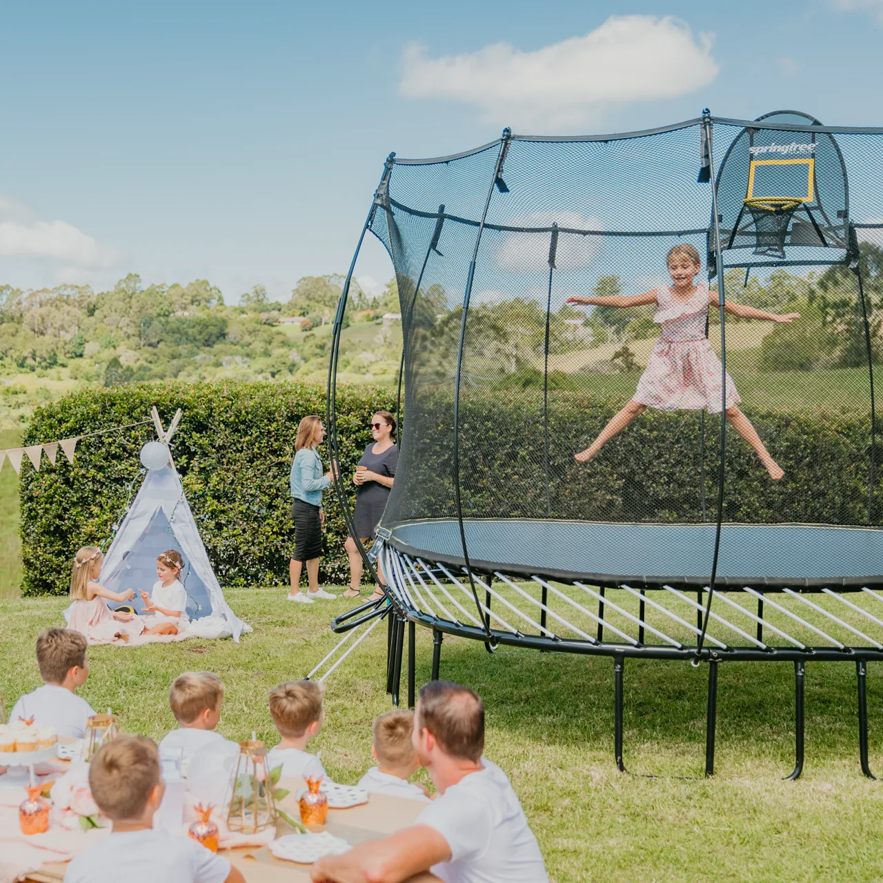 Rodiny u trampolíny Springfree Large Square S113 na zahradní oslavě
