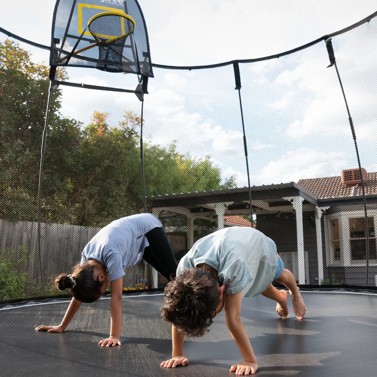 Děti na trampolíně Springfree s basketbalovým košem FlexrHoop
