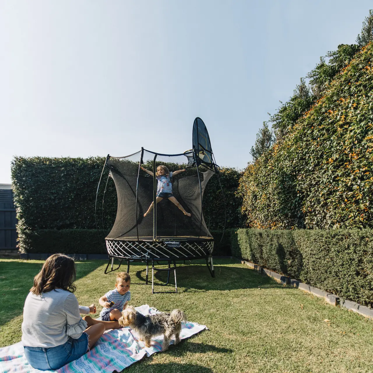 Rodina u trampolíny Springfree Compact Round R54 na zahradě