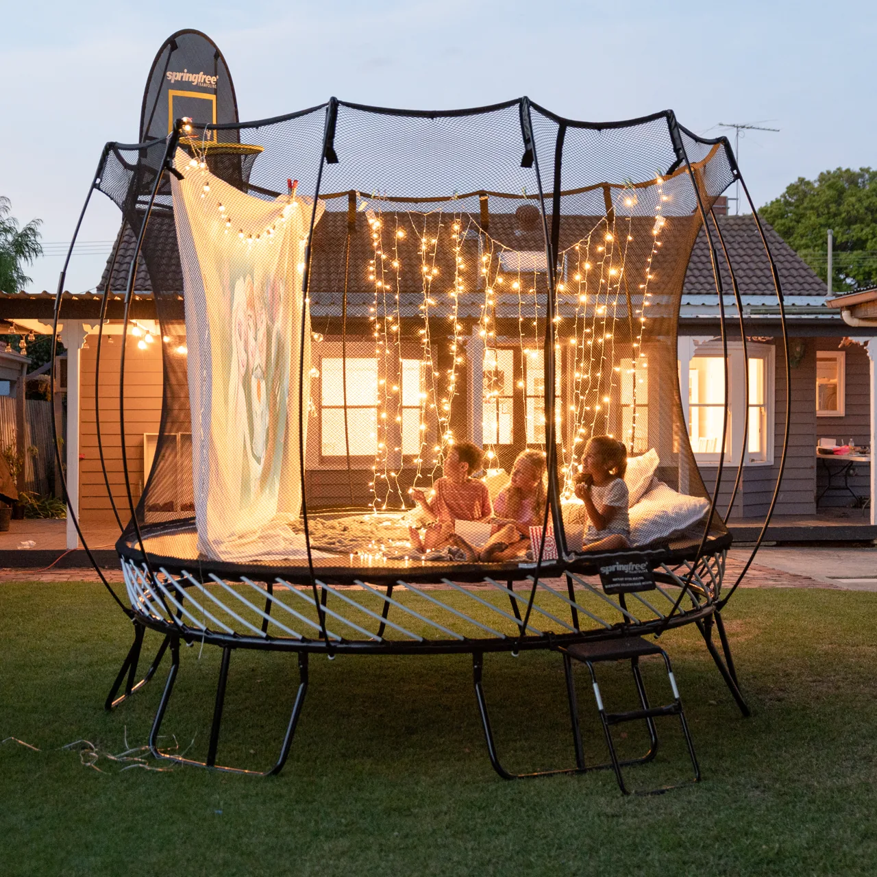 Děti na trampolíně Springfree Medium Round R79 při večerním promítání