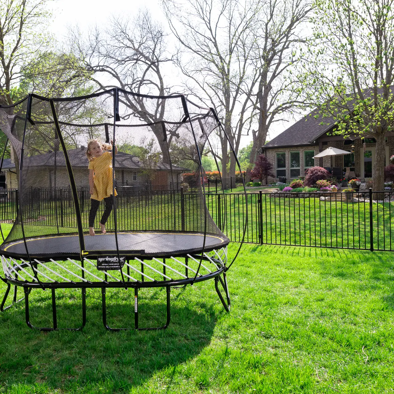 Dítě na trampolíně Springfree Compact Oval O47 na zahradě