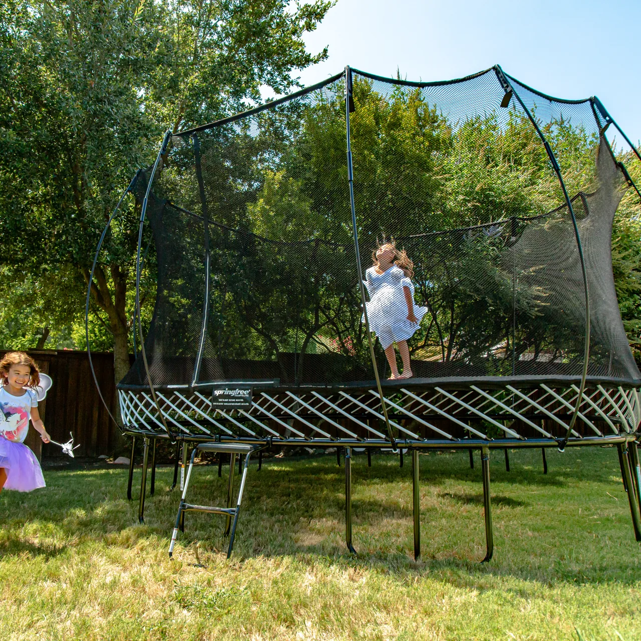 Děti u trampolíny Springfree Large Oval O92 na zahradě