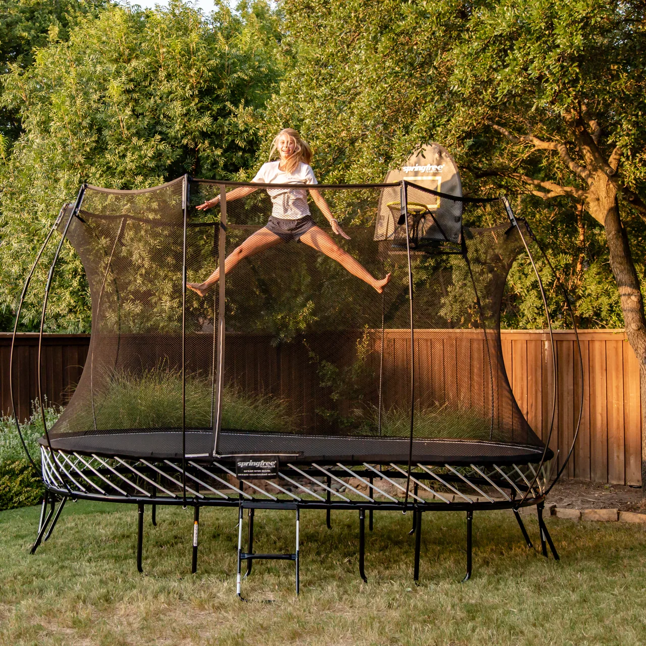 Dítě ve výskoku na trampolíně Springfree Large Oval O92 při západu slunce