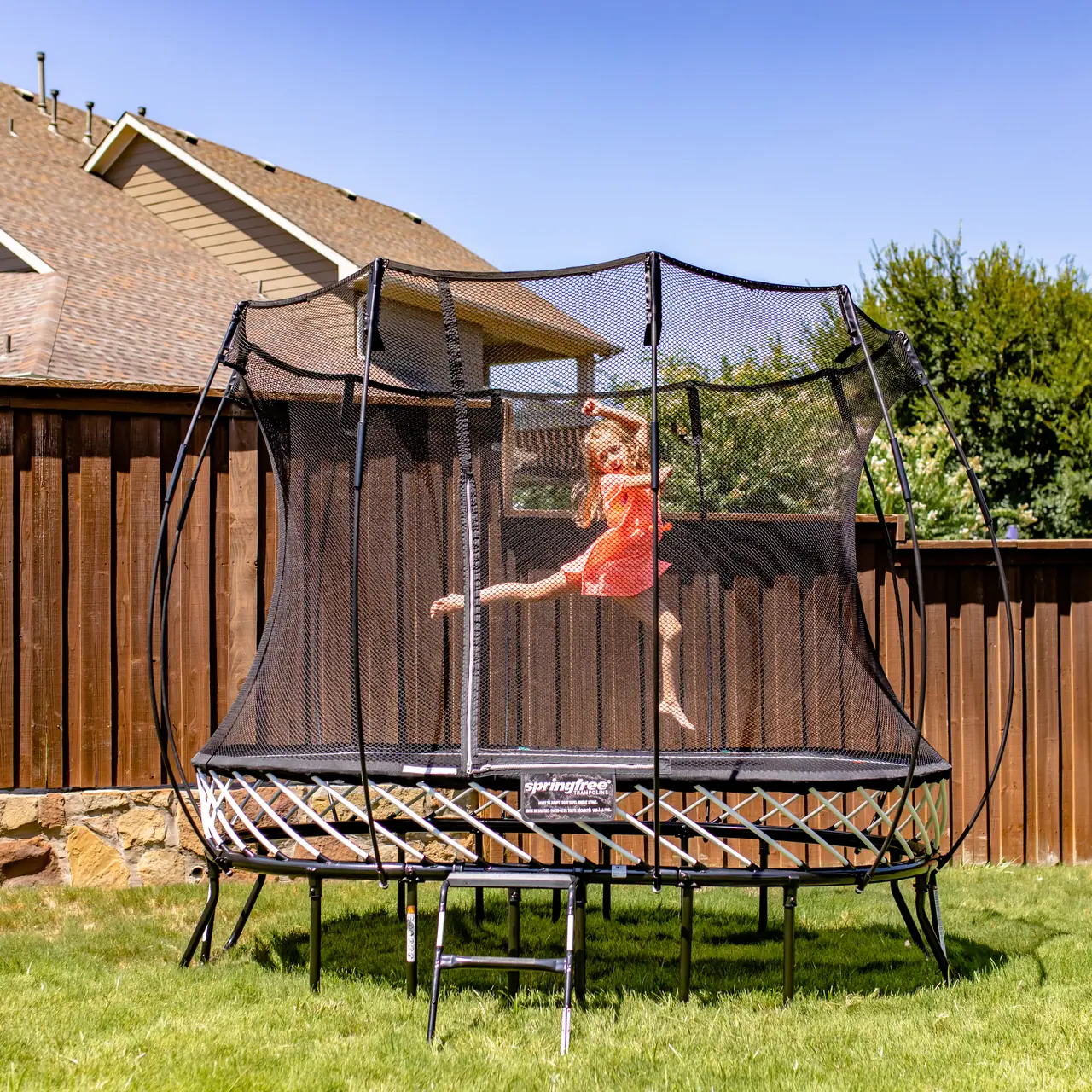 Trampolína Springfree Compact Oval O47 na zahradě s dítětem