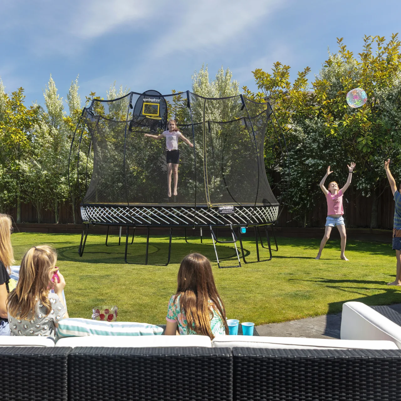 Rodina u trampolíny Springfree Jumbo Round R132 na zahradní oslavě